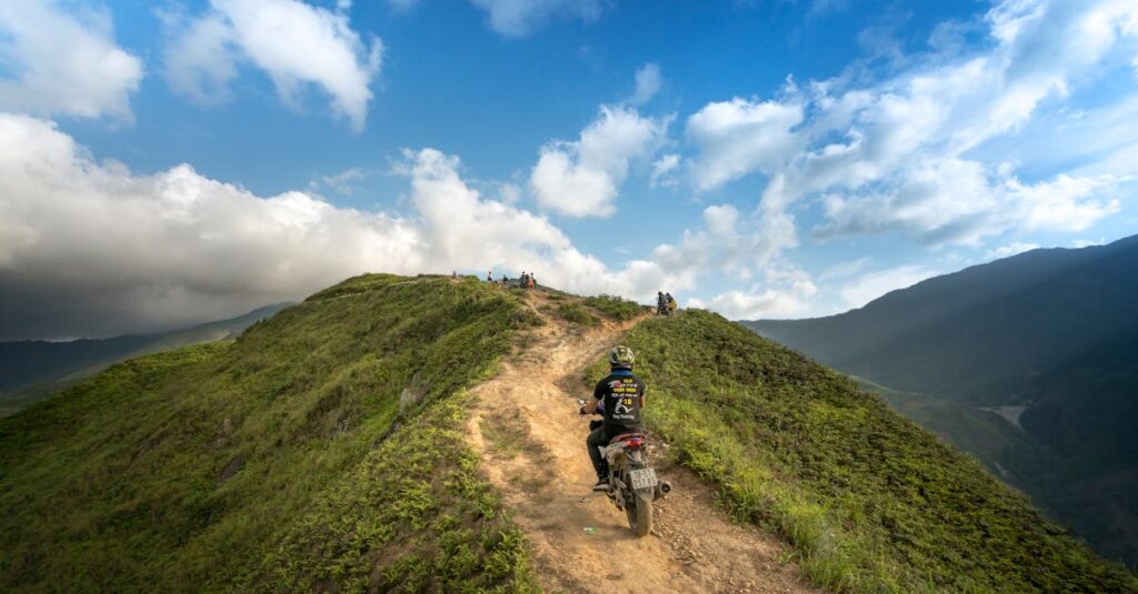 The Golden Triangle Motorcycle Adventure: Riding Through Thailand’s Historic Borderlands A motorcyclist travels along a rugged mountain path under a vibrant summer sky, perfect for adventure enthusiasts.