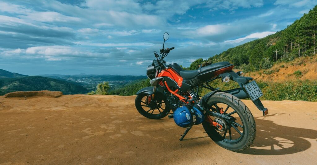 A red motorcycle parked on a mountain roadside with a scenic view under a bright blue sky.