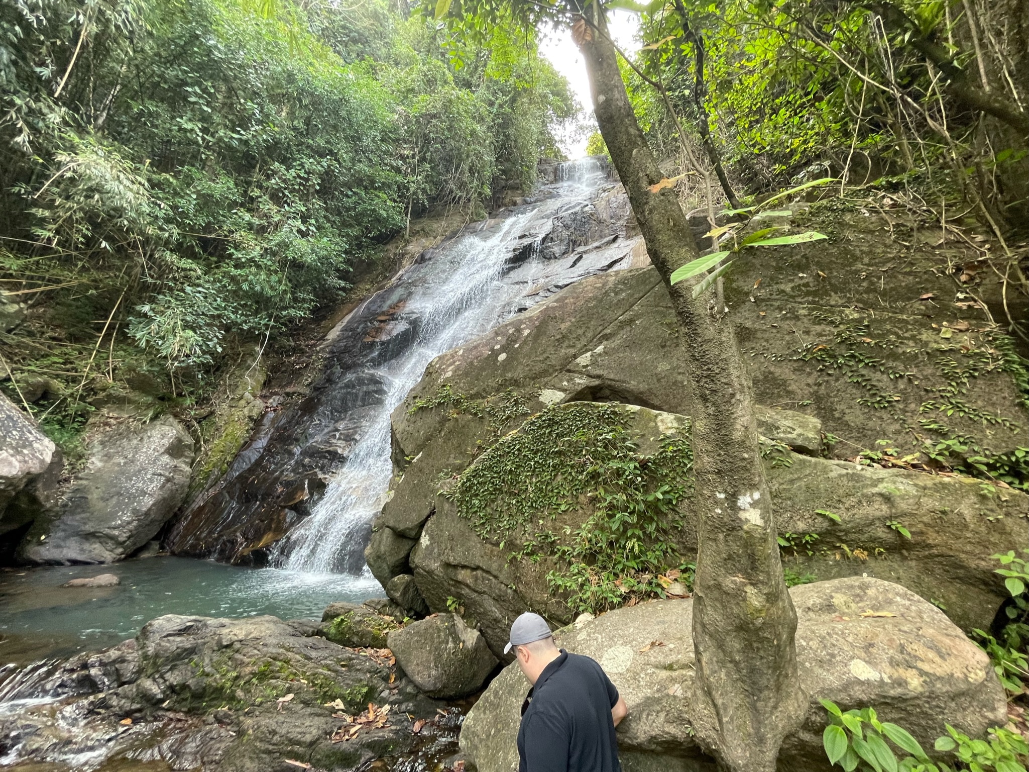 waterfall in koh lanta. Man is trying not to fall on the slippery rocks