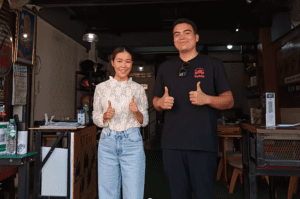 Two people standing outside motorbike rental shop in Chiang Mai. Byklo employee and owner of K7 Bike Chaing Mai giving thumbs up