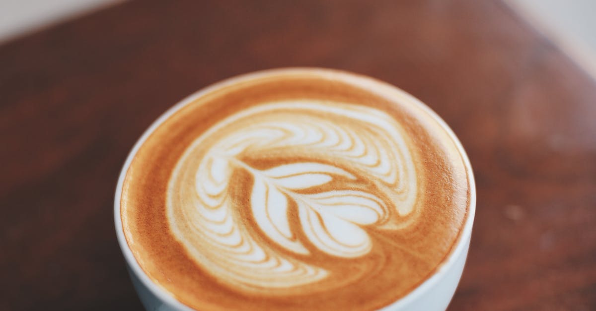 Best coffee shops in Krabi with stunning views A beautifully crafted latte with intricate latte art inside a white ceramic cup on a wooden table.